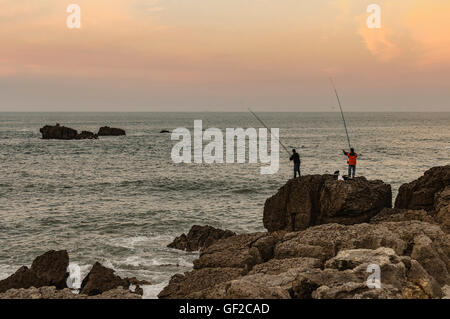 Due uomini la pesca su una grande roccia sulla costa settentrionale della Spagna, Noja Cantabria, Europa Foto Stock