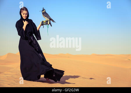 Giovane donna in abaya con falco pellegrino in Dubai Desert Conservation Reserve, EMIRATI ARABI UNITI Foto Stock