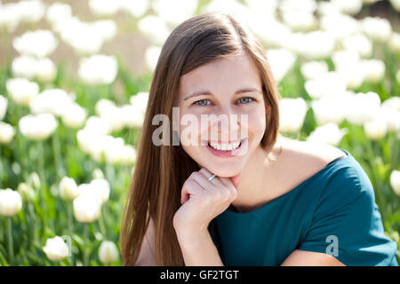 Ritratto di giovane e bella donna di colore bianco su sfondo tulipani Foto Stock