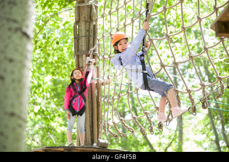 Poco ragazze cinesi in riproduzione in tree top parco avventura Foto Stock