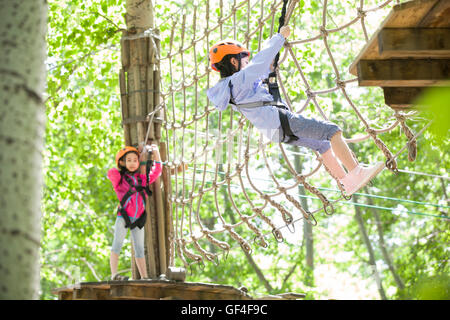 Poco ragazze cinesi in riproduzione in tree top parco avventura Foto Stock