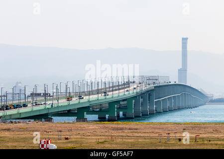 Giappone, Kansai, Aeroporto KIX. Colpo distante dall' aeroporto della strada e rotaia Sky Gate Bridge e il più lungo ponte di travatura reticolare nel mondo. Hazey. Ore diurne. Foto Stock