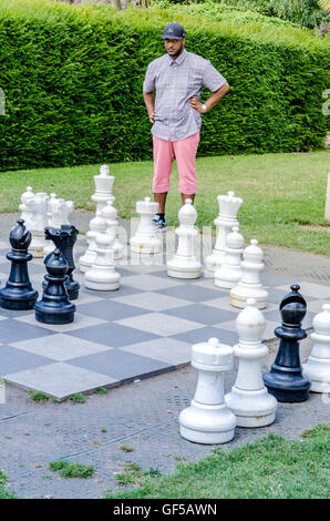 Un ragazzo di giocare una partita a scacchi sulla scacchiera gigante in Holland Park, Londra. Foto Stock