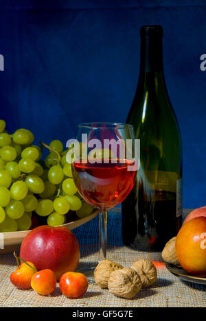 Classic still life con una colorata ciotola di frutta e una bottiglia di vino con un wineglasses su sfondo nero Foto Stock