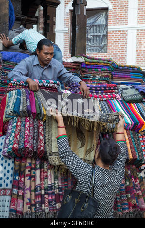 Kathmandu, Nepal - Ottobre 19, 2014: un venditore mostra sciarpe di un cliente sul mercato a Kathmandu in Nepal Foto Stock