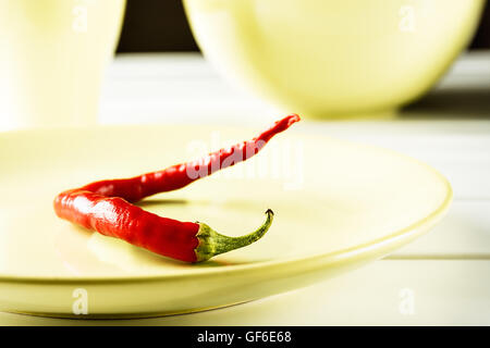 Peperoncino sul piatto verde su legno bianco. L'immagine orizzontale. Foto Stock