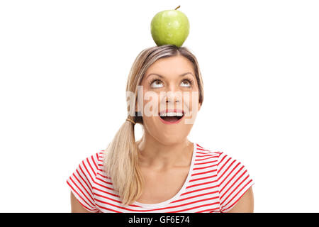 Giovane donna bionda equilibratura di un Apple sul suo capo isolato su sfondo bianco Foto Stock