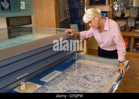 Regno Unito, Inghilterra, Devon, Honiton, High Street, Allhallows Museum interno, visitatore in cerca di pizzo storico Foto Stock