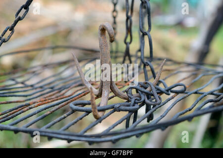 Di ferro arrugginito gancio triplo su griglia appesi a catene. Profondità di campo. Foto Stock