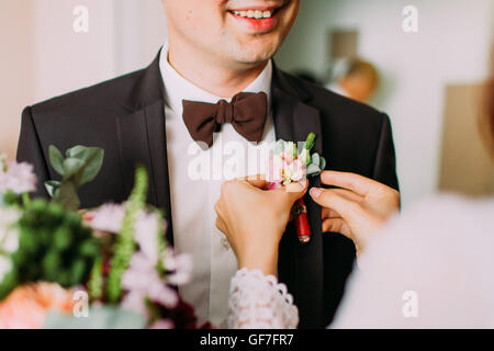 Delicte sposa le mani pin rosa e viola boutonniere per sposi tuxedo Foto Stock