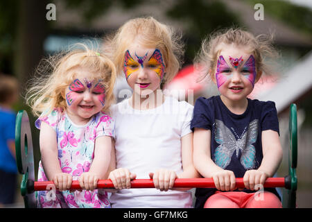 Bambini Bambino kids 3 sorelle le ragazze / ragazza con pittura del viso trucco facce dipinte e i gioielli di artista professionista a parte fair Foto Stock