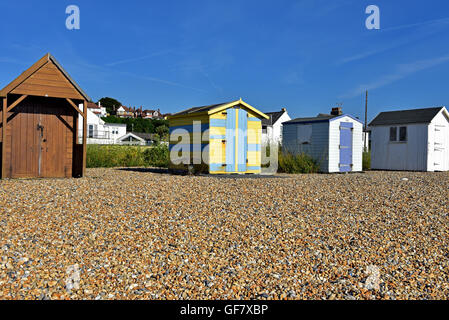 Cabine sulla spiaggia, nella parte superiore di una spiaggia di ciottoli, su alla costa del Kent dove incontra il canale in lingua inglese Foto Stock