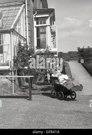 Degli anni Cinquanta, storico,orical, signora anziana in casa di riposo, al di fuori di riposo in poltrona. Foto Stock