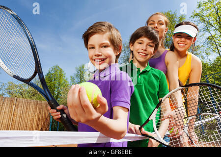 Famiglia giocando a tennis holding racchette e sfera Foto Stock