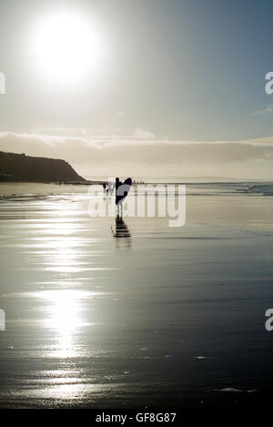 Silhouette di surfer e la gente fuori per una passeggiata mentre il sole tramonta a Ballybunion contea di Kerry Irlanda Foto Stock