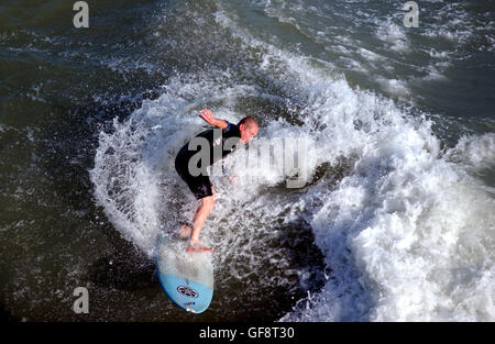 Un surfer fa il la maggior parte della brezza forte e. Mari pesanti in prima serata fuori dalla spiaggia di Brighton vicino Il groyne a ovest del molo di Brighton Foto Stock