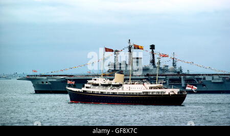 AJAX NEWS FOTO. 1977. SPITHEAD, Inghilterra. - ROYAL YACHT - il Royal Yacht Britannia con H.M.QUEEN ELIZABETH II avviato, vele passato la portaerei HMS Ark Royal durante il 1977 Silver Jubilee revisione della flotta. Foto:JONATHAN EASTLAND/AJAX REF:907450 Foto Stock