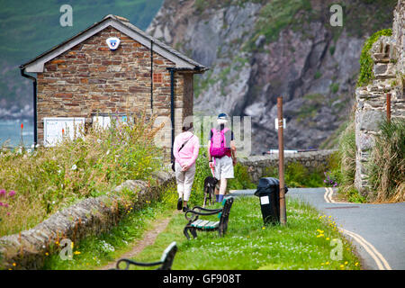 Dog walkers godendo di una passeggiata lungo il sentiero costiero a portwrinkle, Cornwall, Inghilterra, Regno Unito in estate il sole Foto Stock