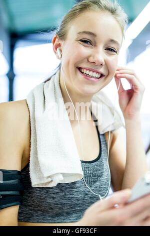 Proprietà rilasciato. Modello rilasciato. Giovane donna che indossa il braccio di regolazione della banda cuffie in palestra, ritratto. Foto Stock