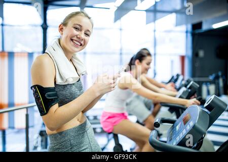 Proprietà rilasciato. Modello rilasciato. Ritratto di giovane donna sms sul cellulare mentre il lavoro in palestra, sorridente. Foto Stock