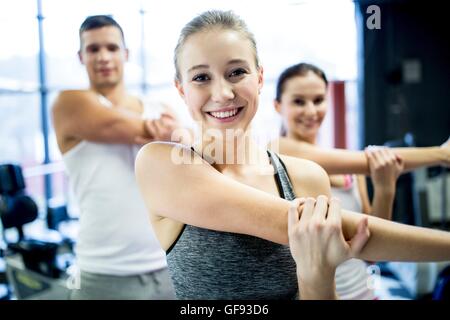 Proprietà rilasciato. Modello rilasciato. Giovani uomini e donne facendo esercizio di riscaldamento in palestra. Foto Stock