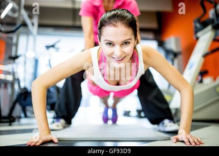 Proprietà rilasciato. Modello rilasciato. Giovane donna facendo premere-ups con l aiuto di un allenatore di fitness in palestra. Foto Stock