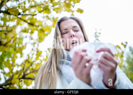 Modello rilasciato. Giovane donna circa al starnuto, gli occhi chiusi. Foto Stock