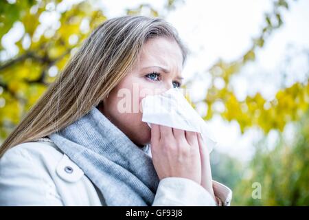 Modello rilasciato. Giovane donna starnuti, close-up. Foto Stock