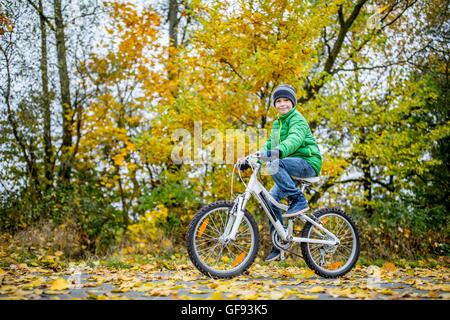 Modello rilasciato. Ritratto di ragazzo in bicicletta nel prossimo autunno. Foto Stock