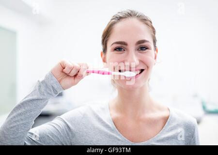 Modello rilasciato. Giovane donna spazzolatura dei denti, ritratto, close-up. Foto Stock