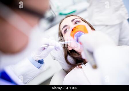 Modello rilasciato. Paziente che riceve la luce ultravioletta procedura al dentista clinica. Foto Stock
