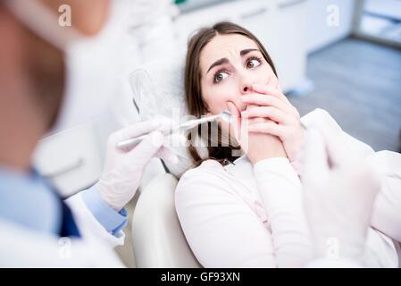 Modello rilasciato. Scioccato paziente guardando al dentista di dentista clinica. Foto Stock