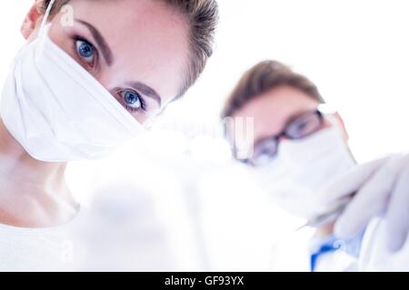 Modello rilasciato. Dentista e assistente che tiene lo specchio inclinato. Foto Stock