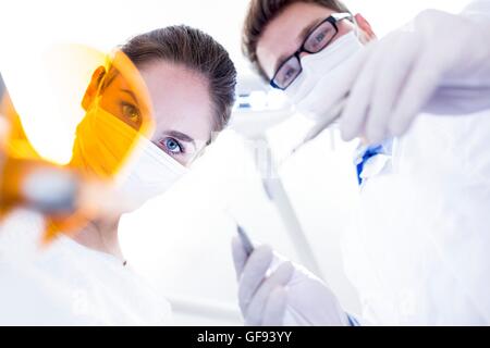 Modello rilasciato. Dentista e assistente che tiene lo specchio inclinato. Foto Stock