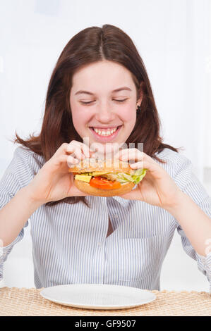 Modello rilasciato. Giovane donna mangiare sano sandwich, sorridente. Foto Stock