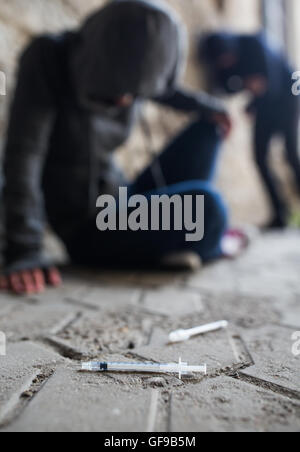 Close up dei tossicodipendenti e siringhe di farmaco sul terreno Foto Stock