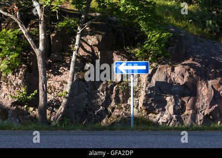 Cartello blu con la freccia sinistra sul lato della strada. Foto Stock