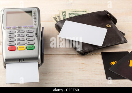 Pagamento terminale senza fili e il portafoglio con banconote sul tavolo moderno Foto Stock