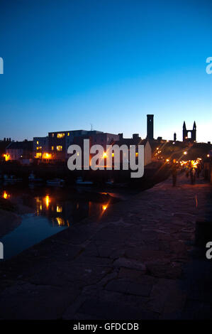 St Andrew's Harbour dal molo al tramonto, con torchlit processione di studenti, Scotland, Regno Unito Foto Stock