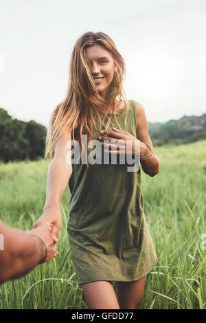 Colpo all'aperto di bella giovane donna in campo con il suo fidanzato. Matura in campo d'erba. Foto Stock