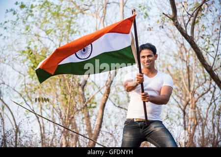 Indian giovane azienda e sventola bandiera indiana, immagine concettuale per il giorno della repubblica o il giorno di indipendenza, uomo bello holding bandiera, uomo indiano di contenimento Foto Stock