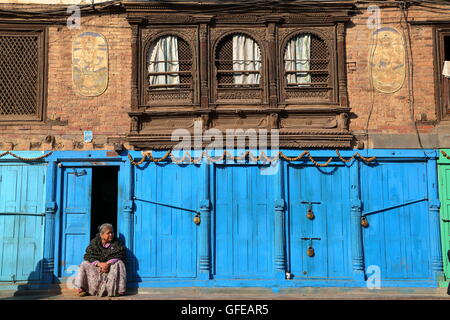 Donna nepalese seduto davanti a casa sua in Patan Nepal Foto Stock