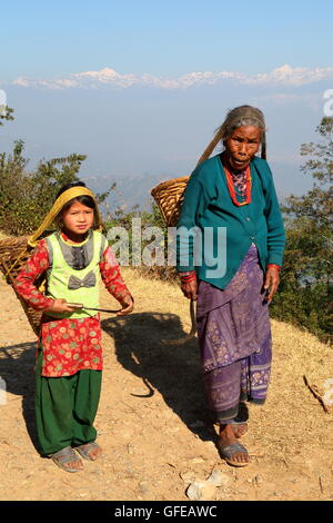 Una donna anziana e una bambina con un cestino sul loro dorso, campagna, Dhulikhel, Nepal, montagna himalayana in background Foto Stock