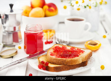 Prima colazione: fresco brinda con in casa Red marmellata di ribes, una tazza di caffè e frutta Foto Stock