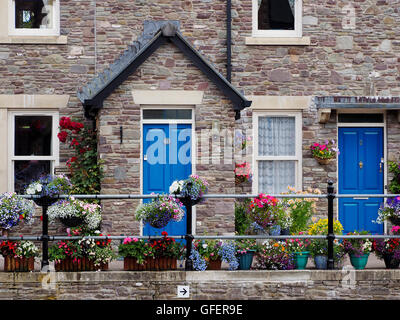 Cottage in pietra con display glorioso di fiori in contenitori di rivestimento del pontile a Brecon bacino sulla Monmouth e Brecon Canal. Foto Stock