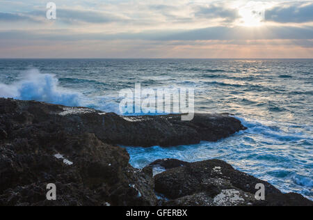 Sera seascape vista dalla riva con raggi di sole nel cielo nuvoloso. Foto Stock