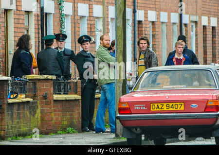 Belfast, Irlanda del Nord. 18 dic 2014 - attori vestiti come Royal Ulster Constabulary (RUC) gli ufficiali e i repubblicani irlandesi stand in una strada a Belfast durante un filmato video riprese. Foto Stock