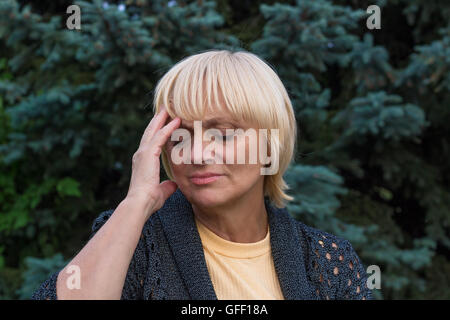 Donna anziana è con un mal di testa e di toccare la sua testa con la sua mano destra Foto Stock