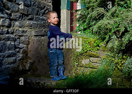 Due anni di vecchio ragazzo appoggiato su una parete Foto Stock