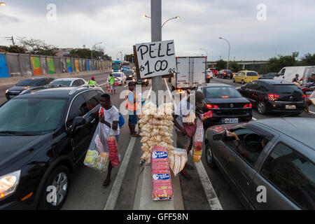 Gli abitanti di Complexo da mare, un enorme rete di favelas che affiancano la Linha Vermelha ( Linea Rossa ), la principale autostrada per l'aeroporto internazionale di Rio de Janeiro al centro della città, il lavoro come venditori ambulanti durante le ore di punta al expreessway - dal 2010 la comunità è stata recintata dall'autostrada da enormi pannelli di Perspex - secondo le autorità forniscono una barriera acustica, la gente del posto lo descrivono come un "muro della vergogna", un altro modo di nascondere i poveri. Foto Stock